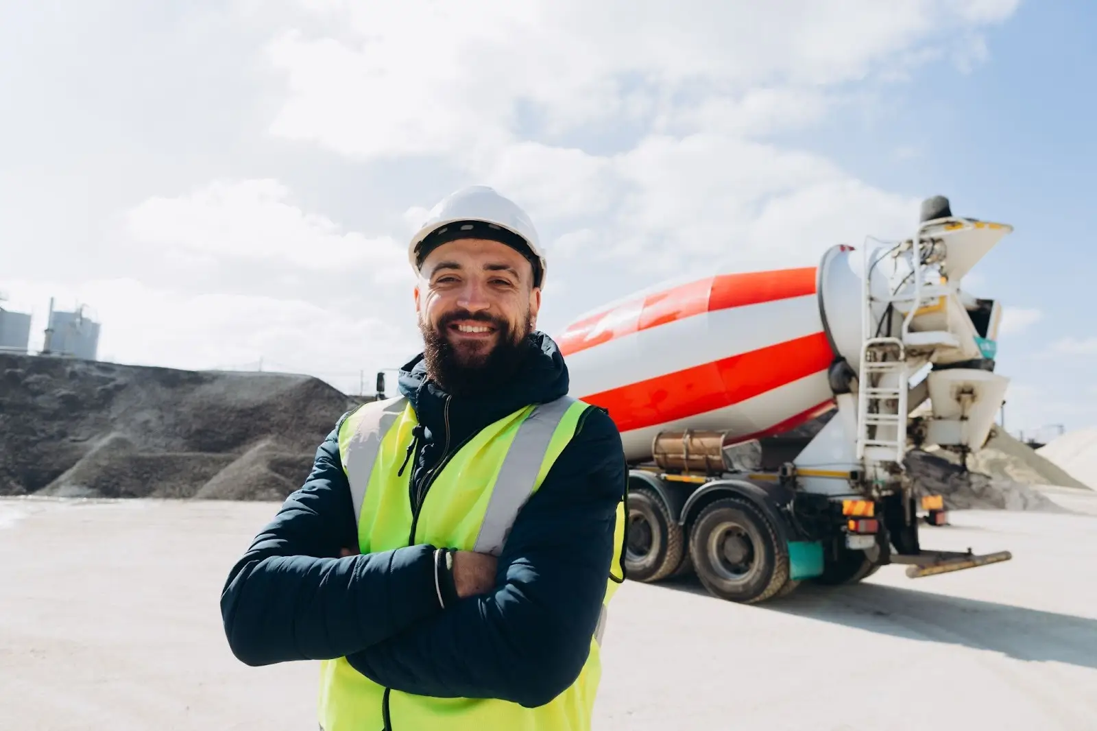 A concrete company worker smiles in front of a cement mixer truck.