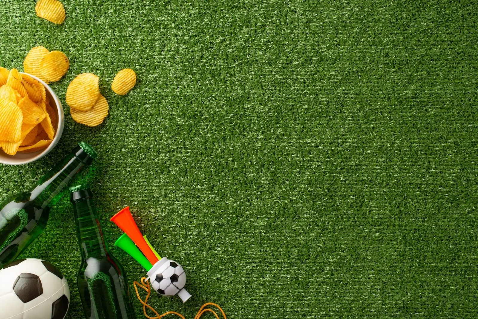 Drinks, snacks, and sports paraphernalia sit on an artificial grass installation.