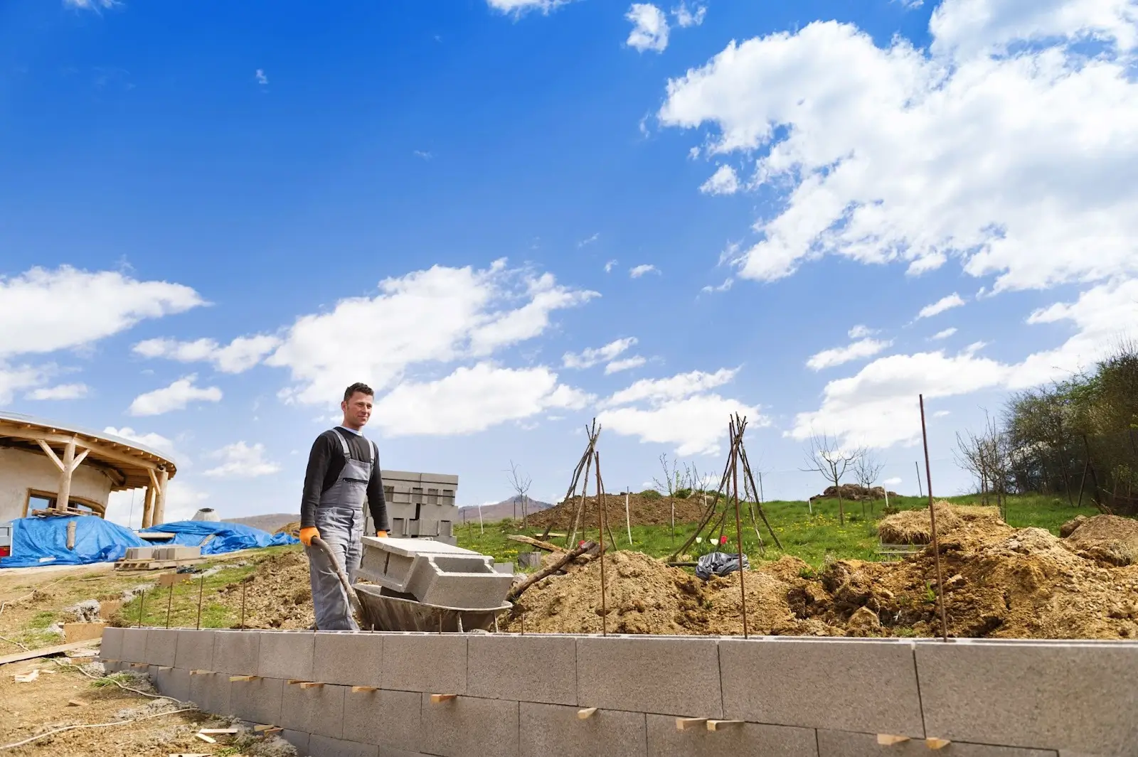 Bricklayer wheels over more blocks to support a concrete retaining wall.