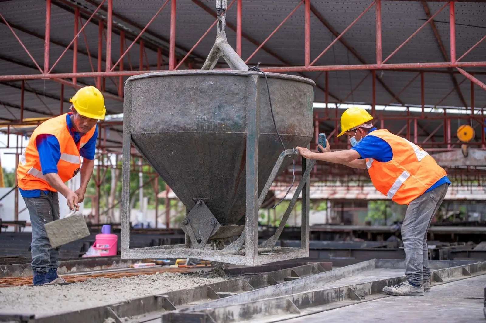 Concrete company workers in safety gear pour and level concrete.