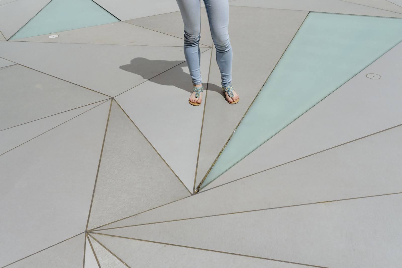 A woman stands on geometric-stamped concrete.